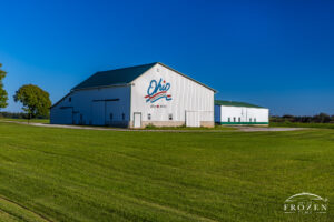 A modern siding finish to an old barn preserves the 100-year old original, where the white siding and green lawn contrast nicely with the evening blue sky and the red, white and blue Ohio Bicentennial logo greets travelers along State Route 309.