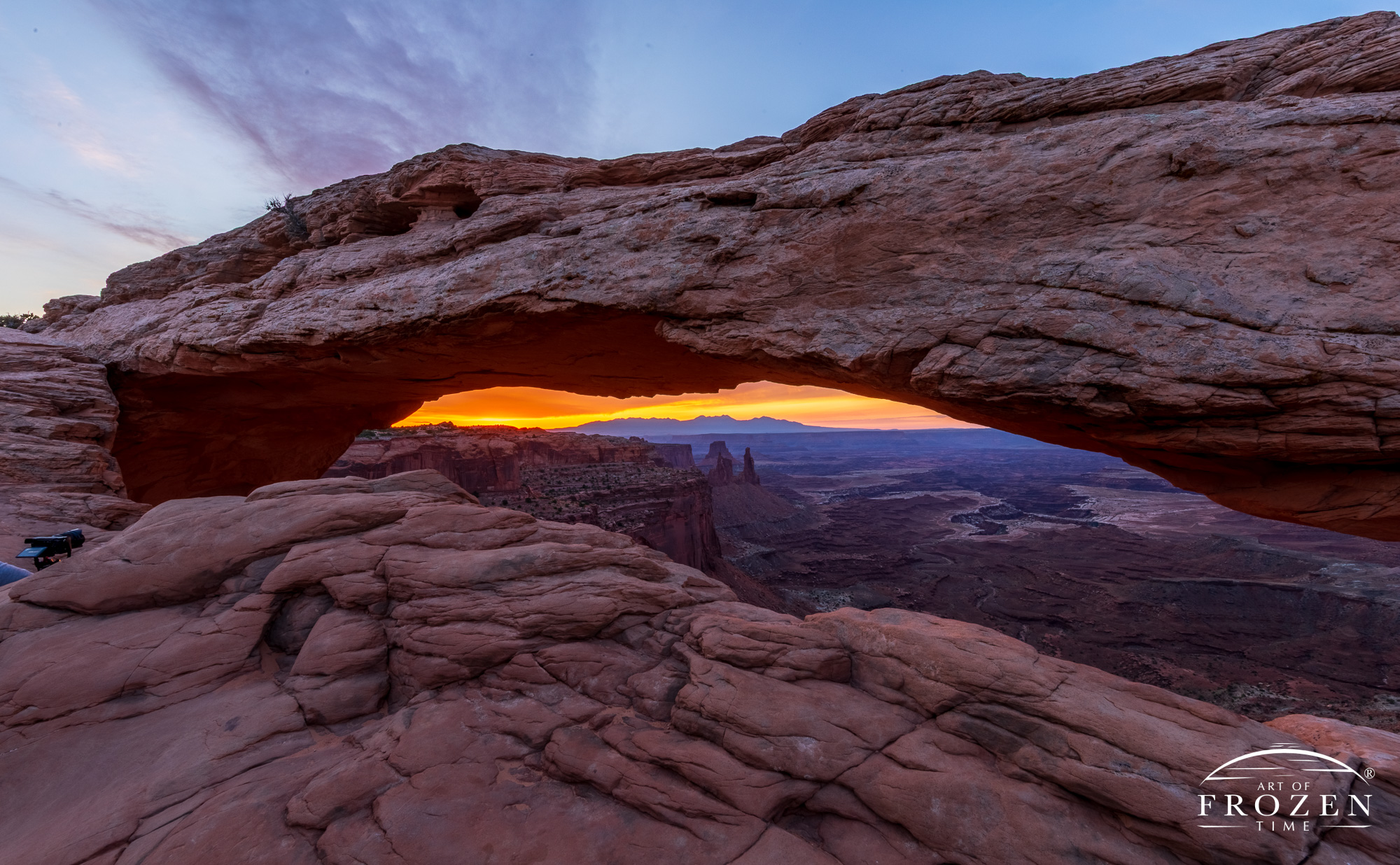 A Canyonlands National Park sunrise where Mesa Arch frames the sunrise over the La Sal Mountains. With the sun still below the horizon, the peak colors are still a couple minutes away.