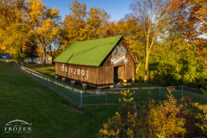 A black barn with a green metal roof displays the Ohio Bicentennial logo on a fall evening where the warm light paints everything in a golden hue