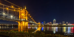 A night view where the Roebling Bridge leads the eye across the Ohio River towards the Cincinnati Skyline