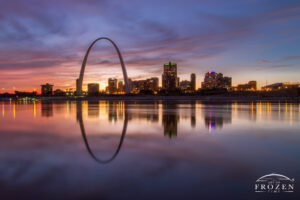 A unique twilight view of St Louis Missouri where the smooth Mississippi River perfectly reflected the St Louis skyline and Gateway Arch following a colorfully impressive sunset