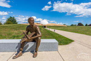 A bronze statue of Neil Armstrong as a 15-year-old sitting on a bench and holding an airplane