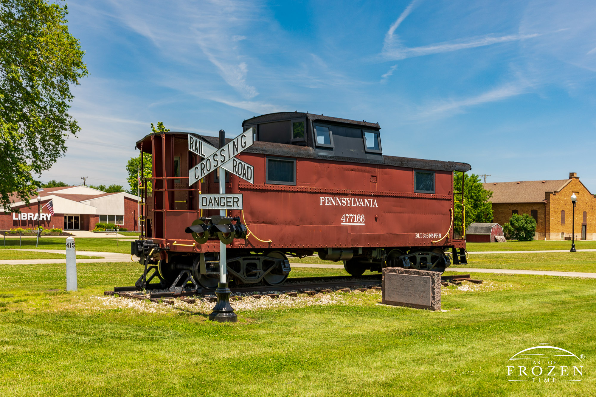 A brown colored Pennsylvania Railroad Caboose stands on a short stretch of tracks in Bradford Ohio