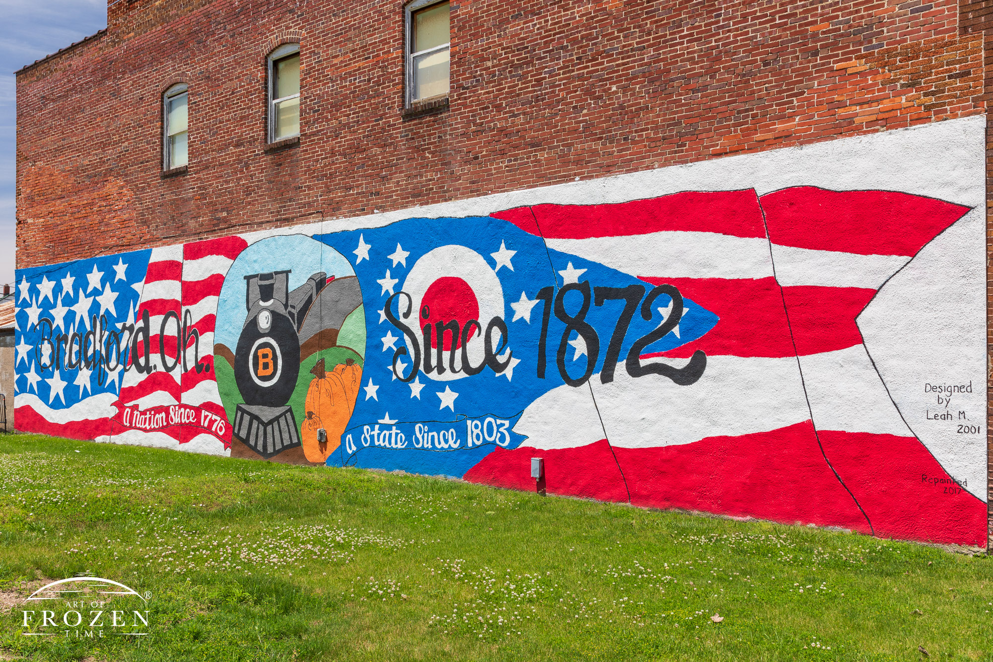 A red, white and blue mural installed on the side of a red-brick building celebrating Bradford Ohio’s railroad heritage.
