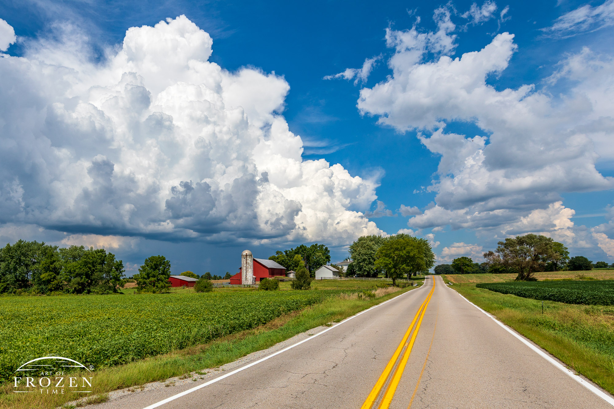 As this country road leads the eye to the distant horizon, an Ohio farm resides under blue September skies and puffy towering cumulus clouds