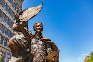 A bronze sculpture of Alexander Hamilton standing along Hamilton, Ohio’s High Street featuring a long cape made from the 13-star US Flag