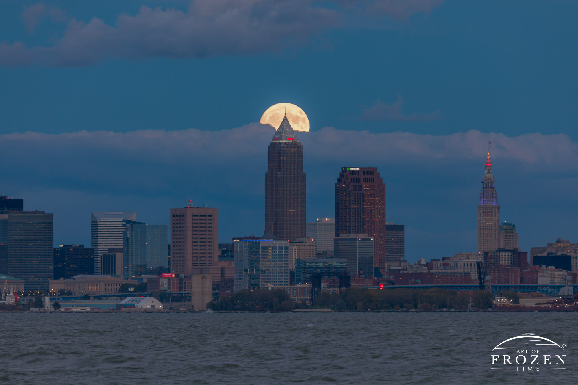 Twilight over Cleveland Skyline from Lakeview Park where a full moon rises between the low stratus clouds and skyscrapers