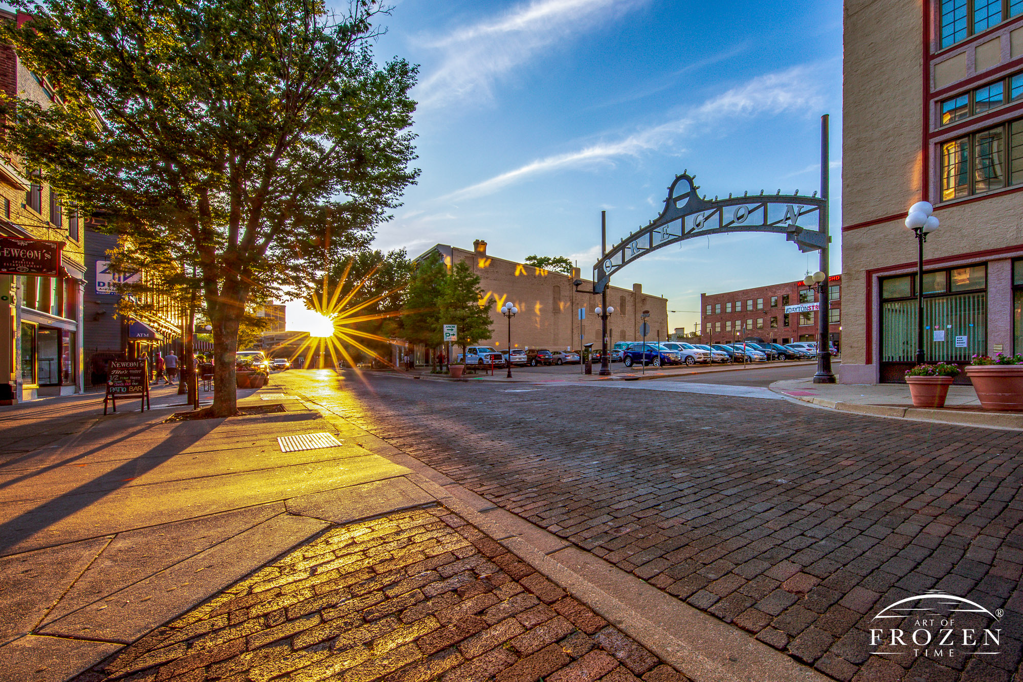 On this summer evening, the sun’s warm rays paint the architectural gem in golden light as the district’s iconic arch sign stands proudly over the brick-paved street
