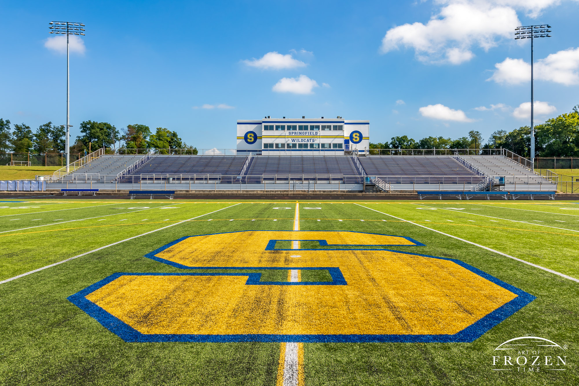 Wide angle views of Springfield Wildcat Stadium on a sunny day featuring artificial turf and the school’s blue and yellow colors.