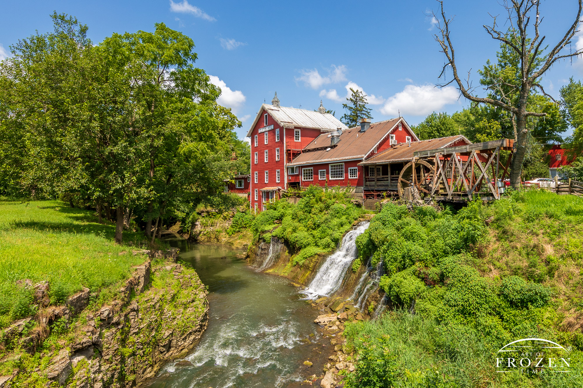 As the Little Miami River powers this grist mill, the red exterior, green plants and blue skies form complementary colors in a classic Ohio scene