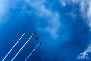 A flight of various WWII aircraft flying in formation as stormy skies part revealing the burning blue sky above