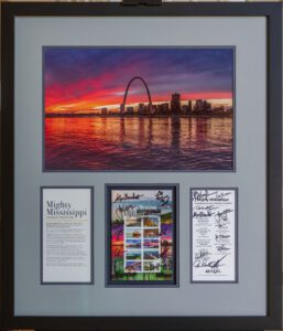 A framed print of a first day of issue stamp with signatures of attendees from the first-day ceremony matted with the original print of the St Louis Skyline