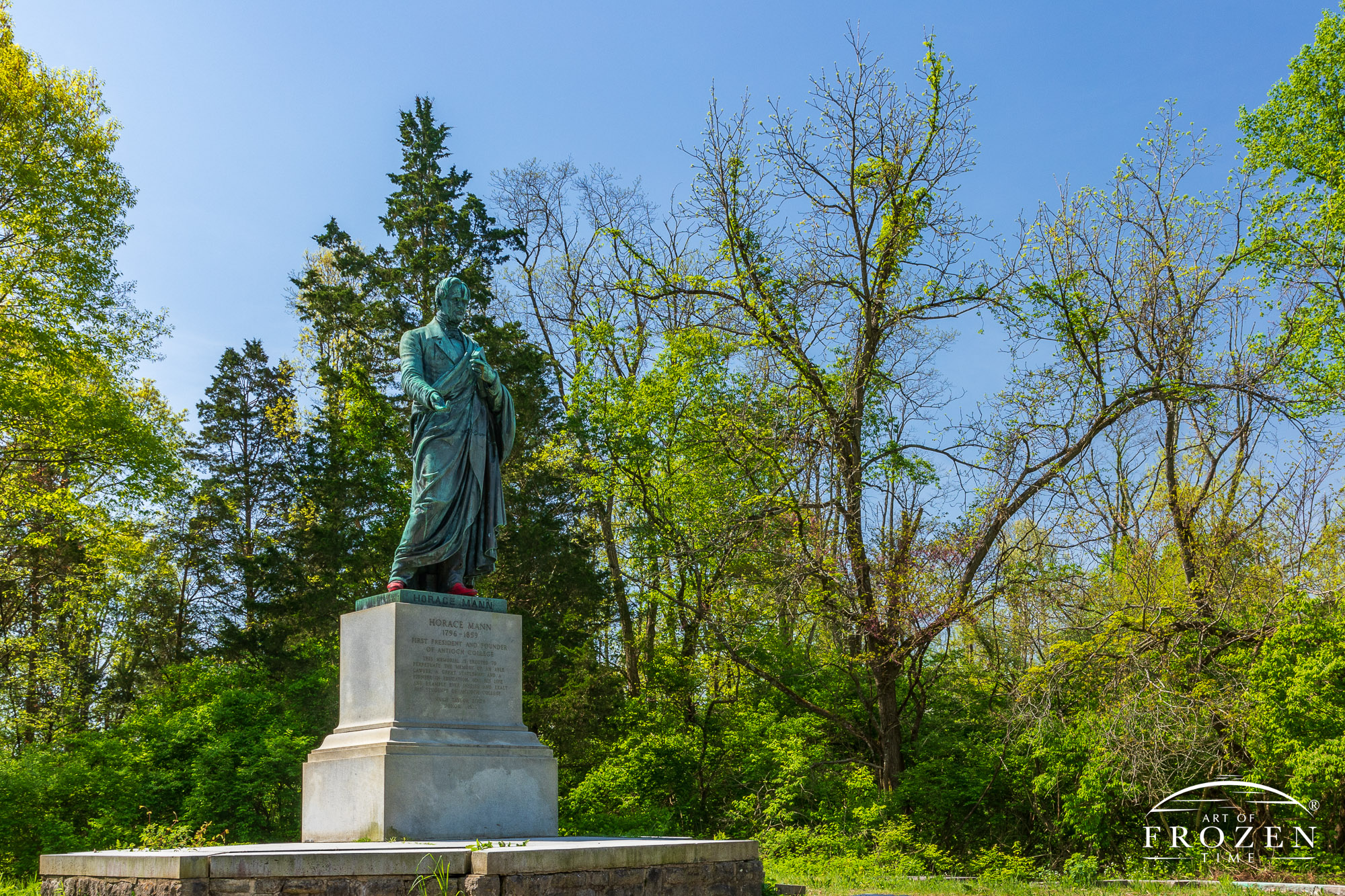 As spring trees leaf out in Glen Helen Nature Preserve a Horace Mann sculptures bask in the sun under blue skies