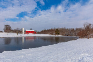 A classic red barn under blue skies and surround by fresh snow