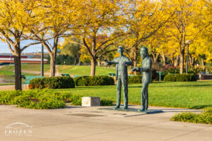Statue of the Wright Brothers surround by trees taking on their autumn color in evening light