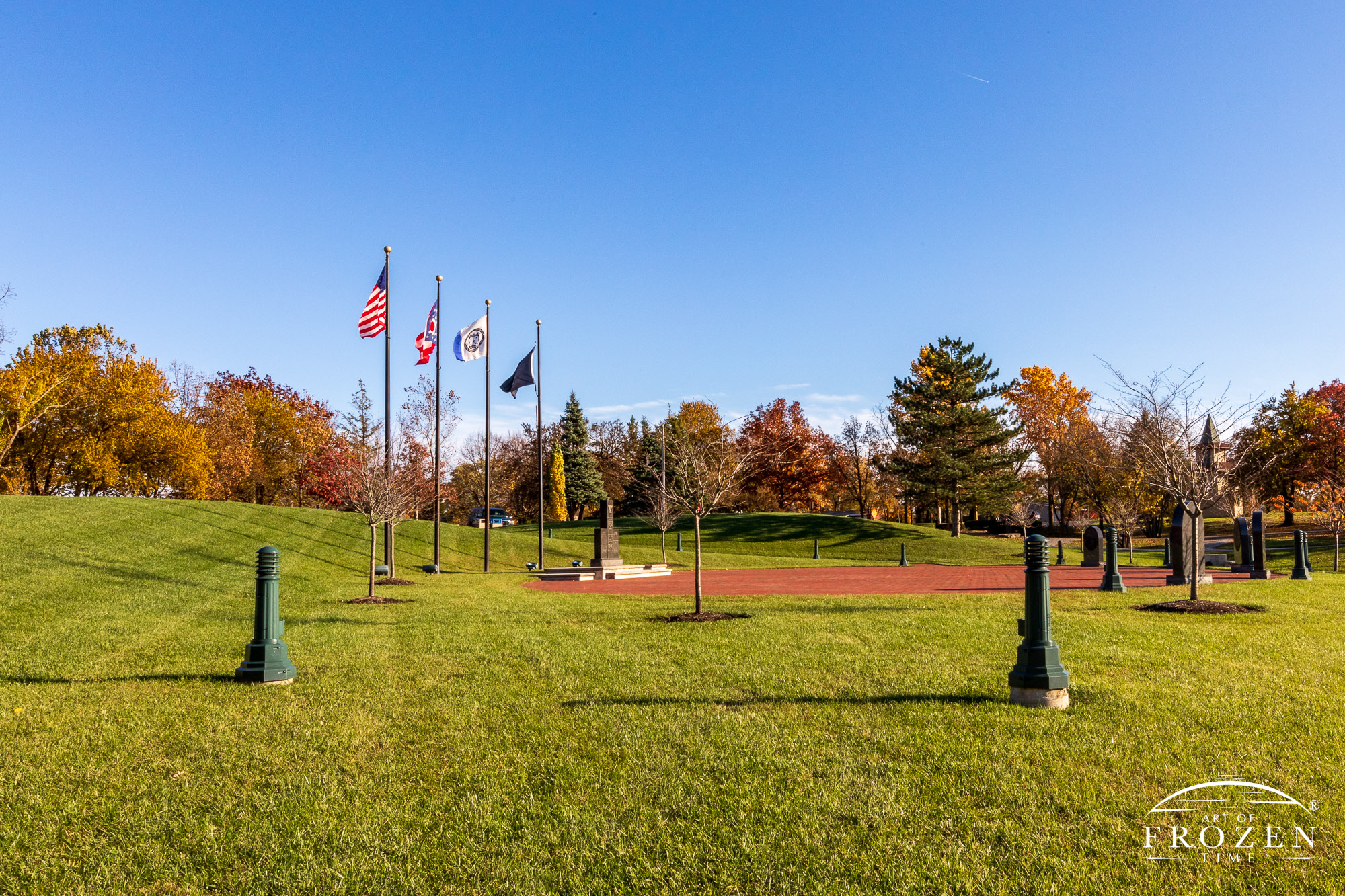 An evening image of the Centerville Ohio Veterans Memorial where the golden light enriches the autumn colors and a gentle wind lifts the flags from the pole.