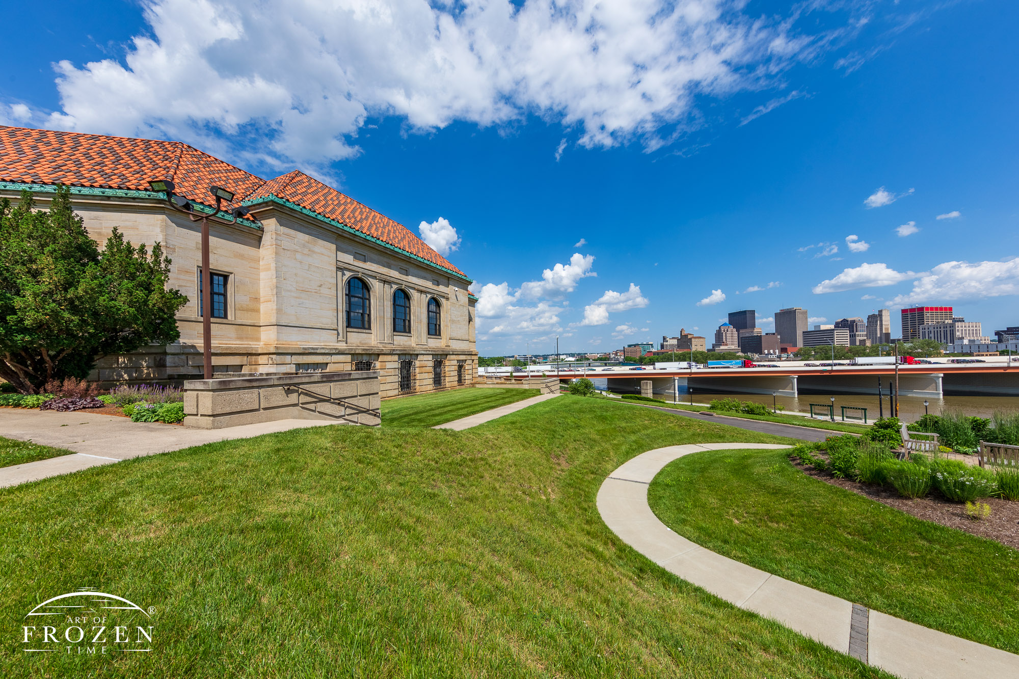 The facade of the Dayton Art Institute on a gorgeous June Day with the DAI and the Dayton Skyline basking in the sunlight as clumulous clouds float through the blue sky