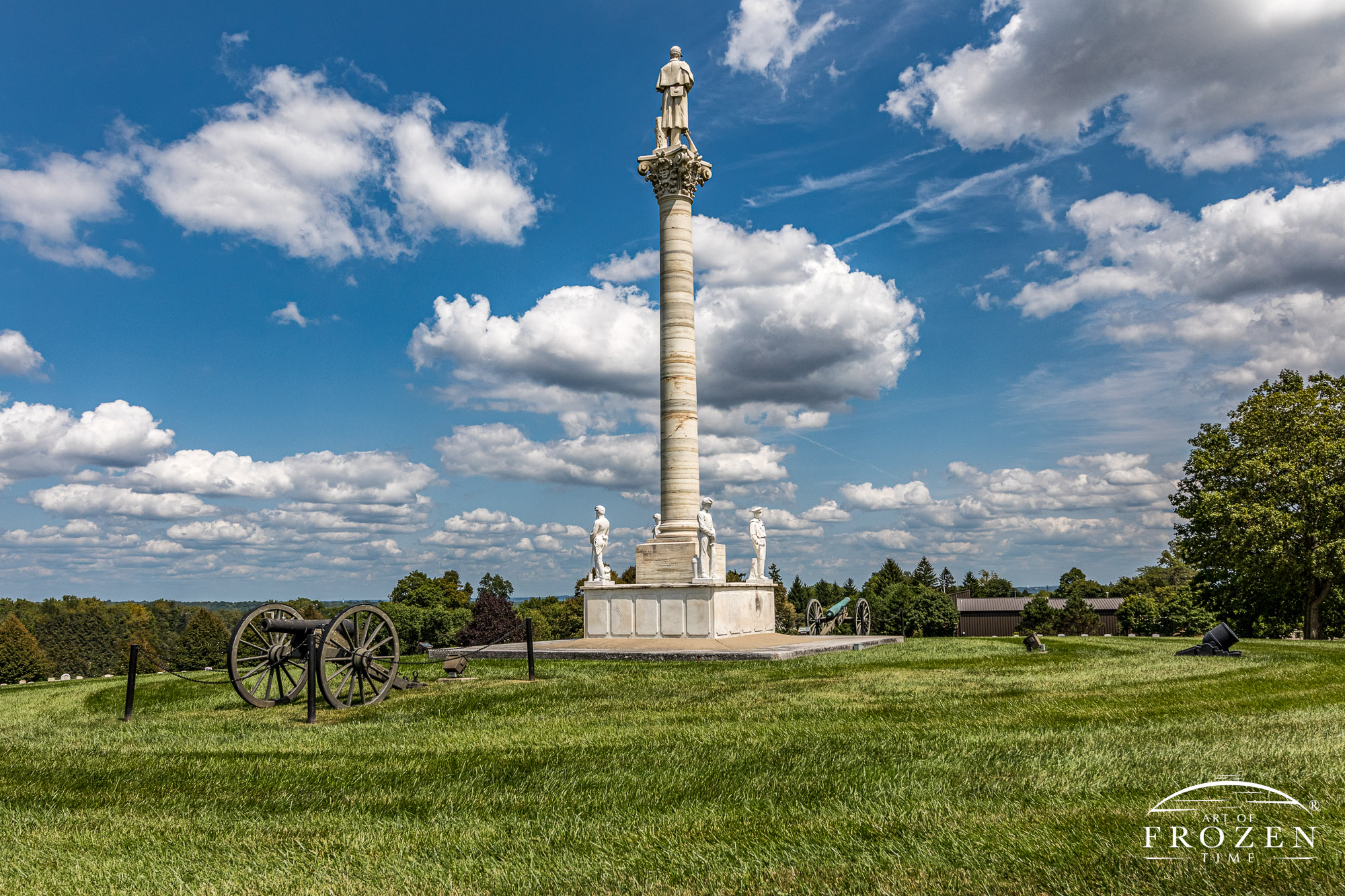 A perfect summer day featuring a white column monument with a Civil War Soldier perched under blue skies and cumulus clouds staring off to the eastern horizon