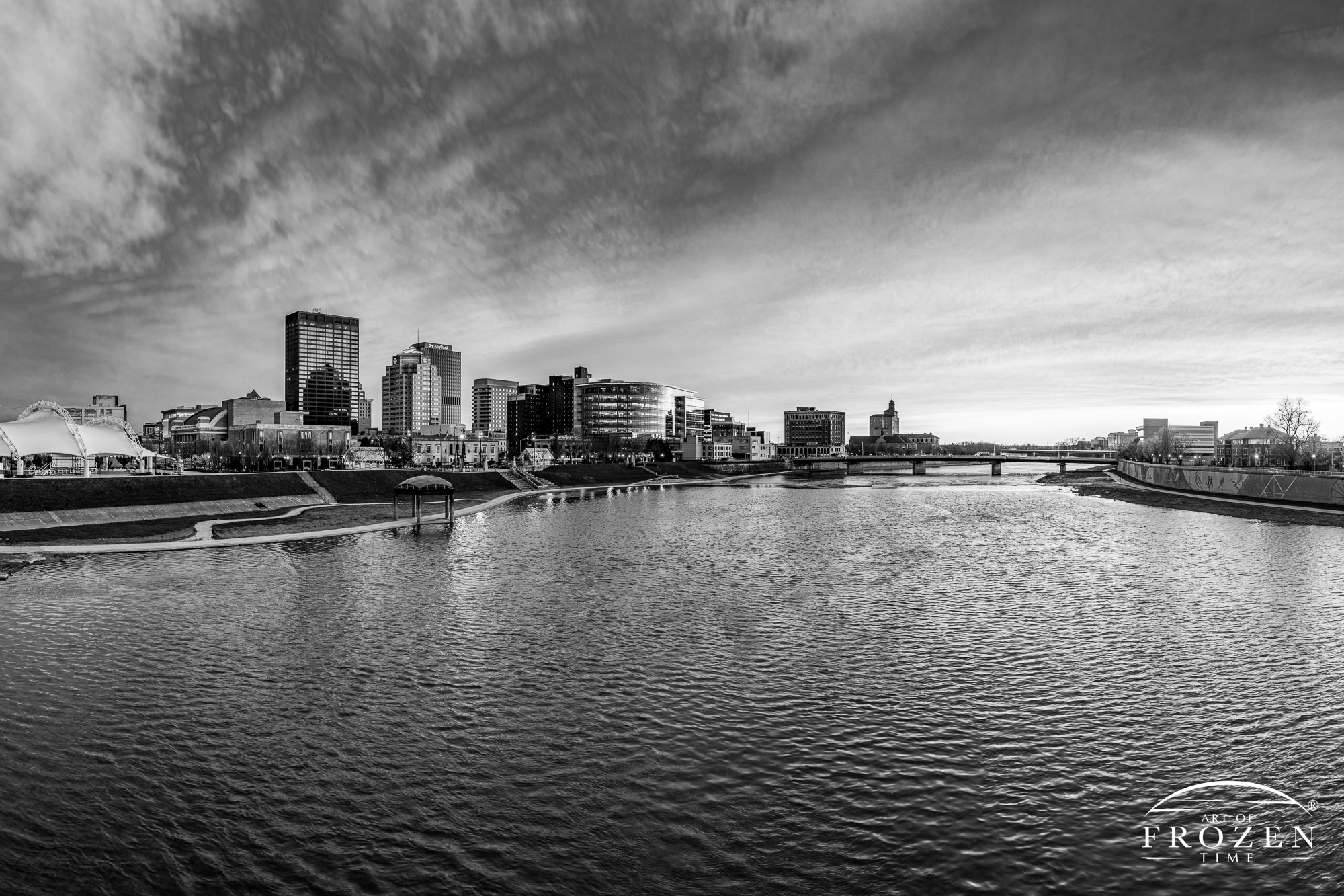 A black and white view of the Dayton Skyline during a windy sunset where the sun illuminated the underside of the clouds