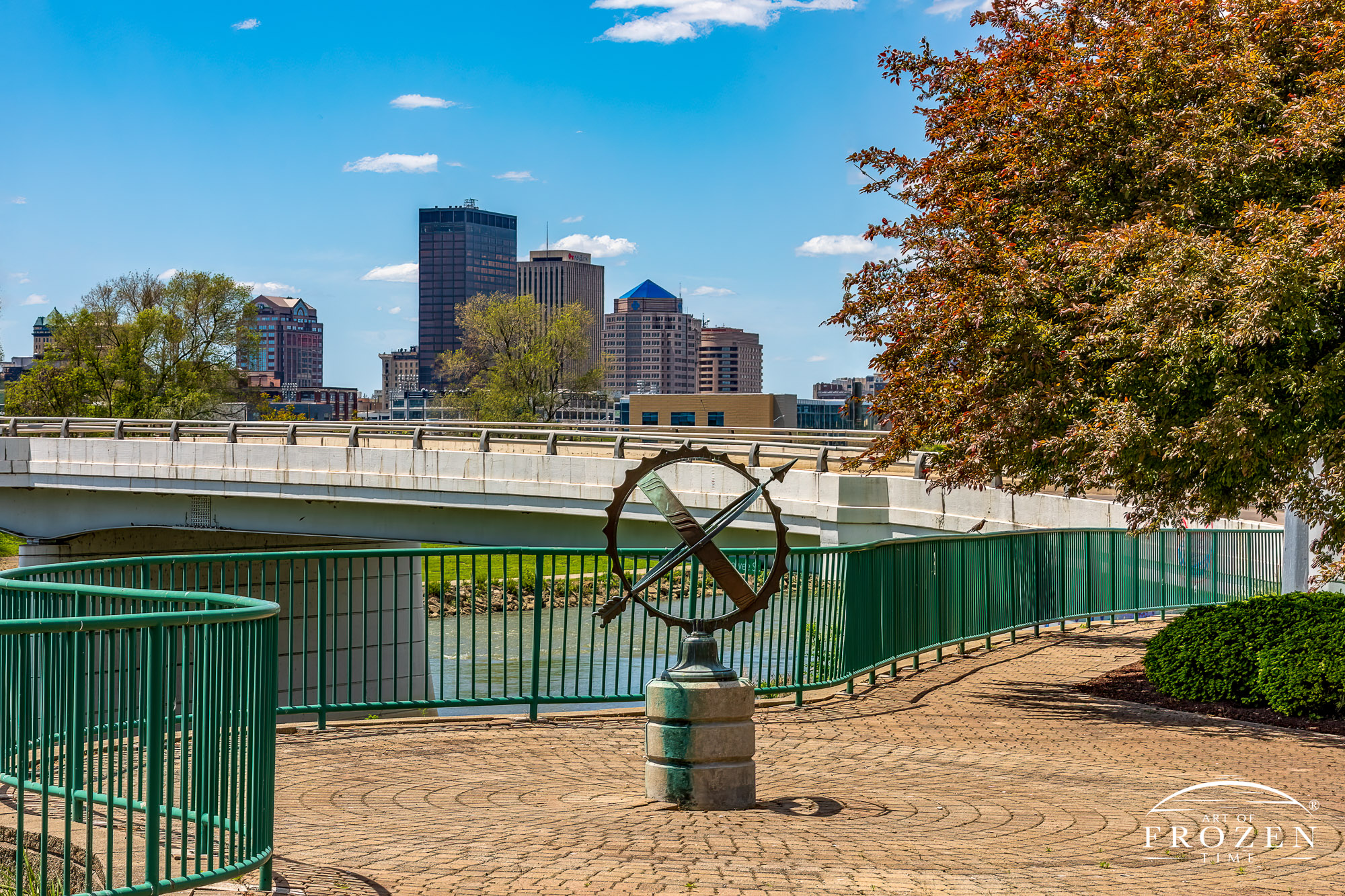 A pleasant spring day from the Joseph R Kanak Park at Valley and Keowee streets where a bronze armillary stands on a pedestal in front of the Dayton Skyline