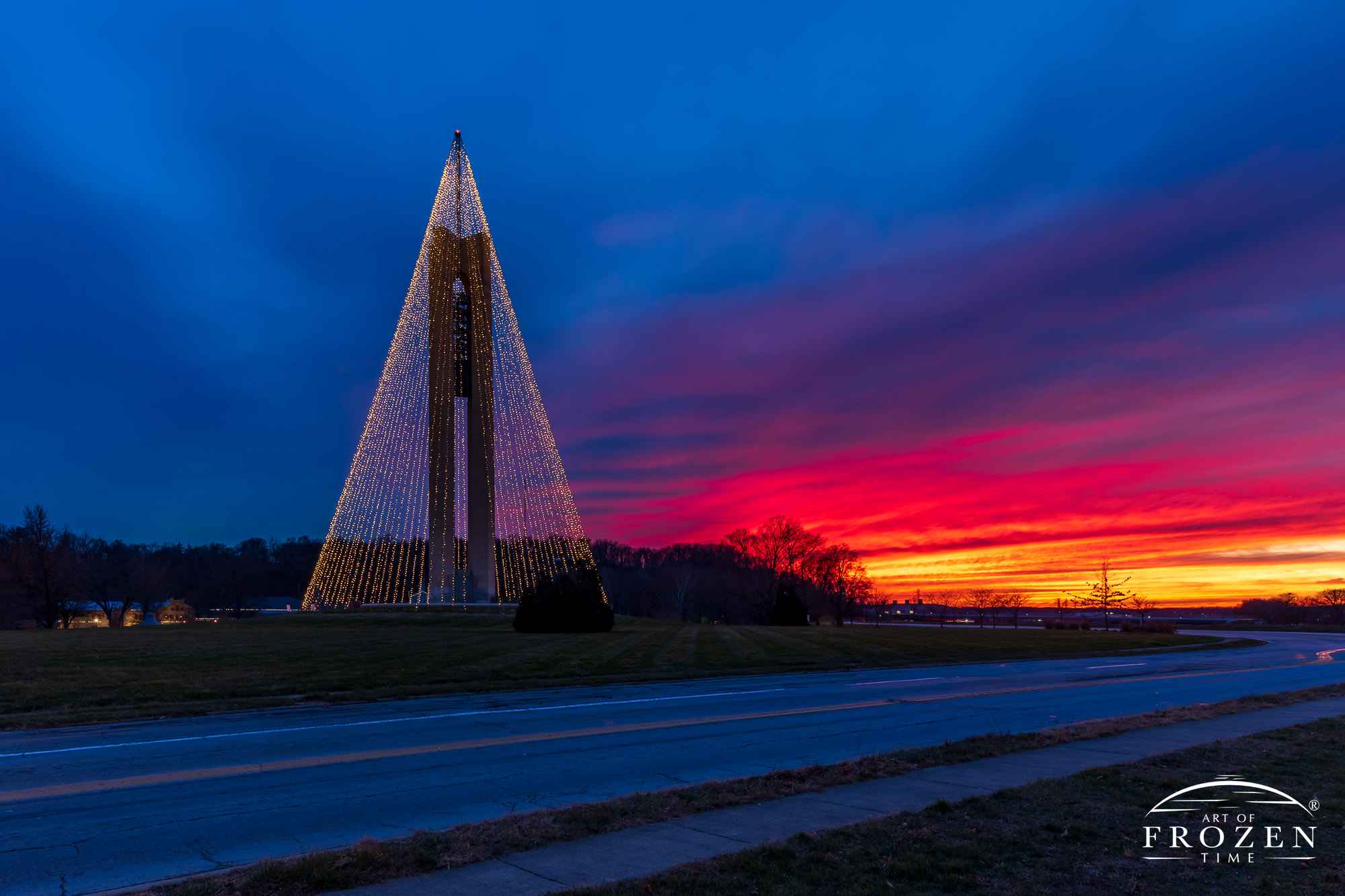 Dayton's Belltower adorned with Christmas lights during a fiery sunset