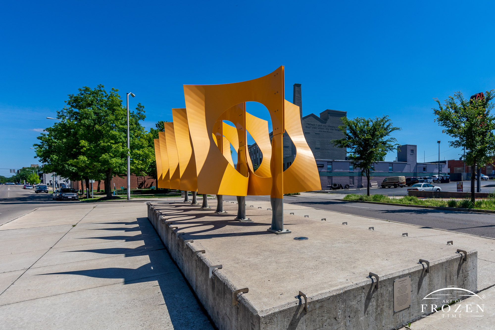 A bright yellow sculpture in Dayton Ohio consisting of 6 laser cut aluminum panels depicting the natural flow of water and air