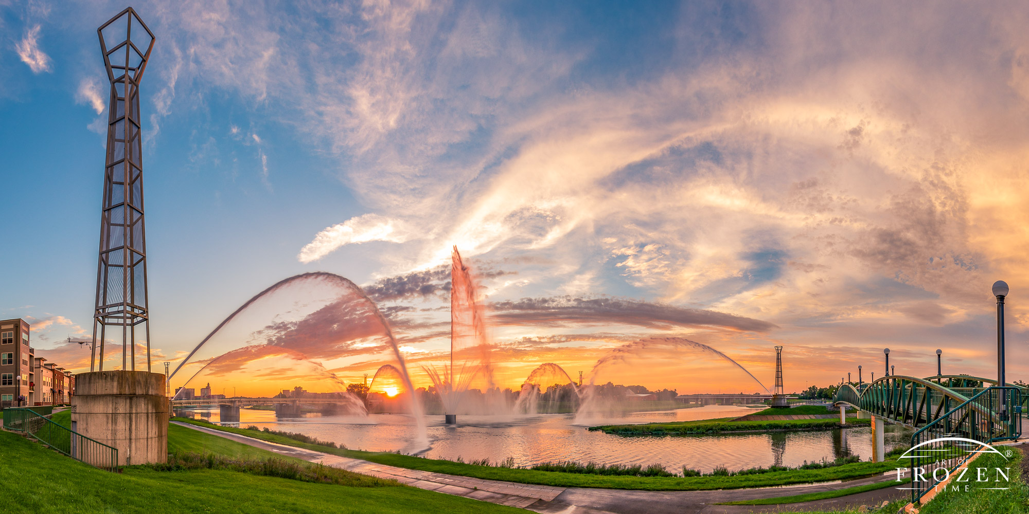 Dayton’s Fountain of Lights panorama erupting during colorful sunset where the fountain sprays catch the warm sunlight
