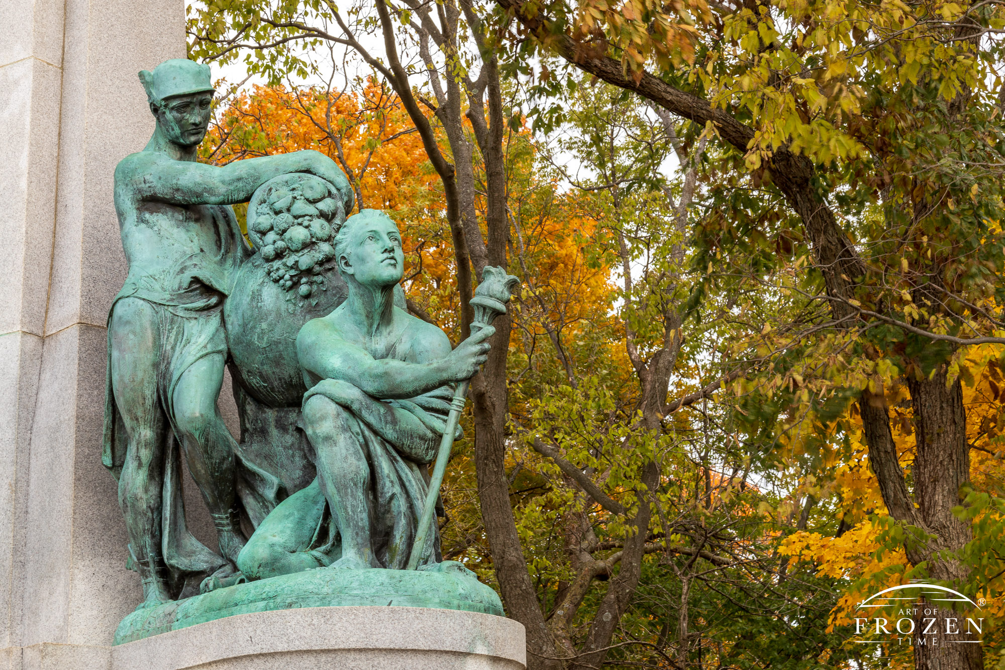 A bronze subgroup of John H. Patterson’s Memorial depicting two men, one holding a cornucopia on a globe while the other kneels and holds a torch and stares skyward, symbolizing Patterson’s progress and prosperity pursuits.