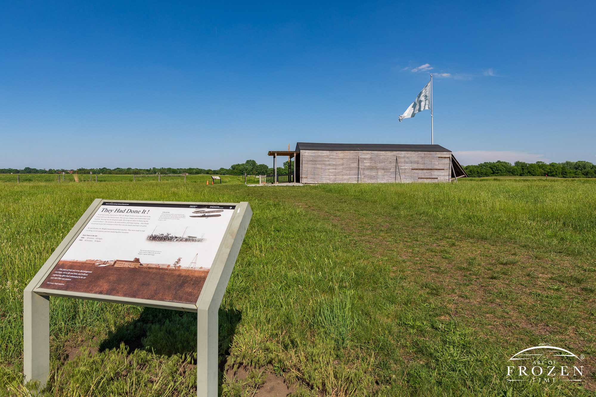 A summer view of replica Wrigth Brother hanger as it sits on Huffman Prairie under blue skies