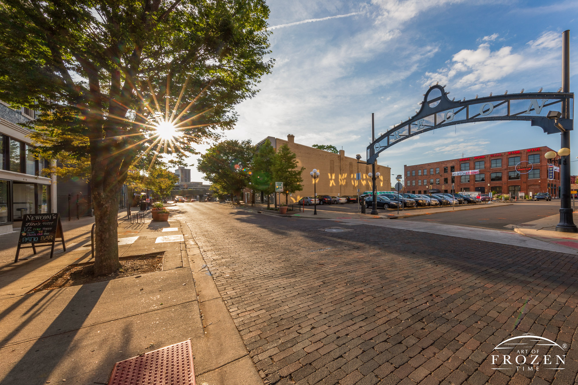 On this summer evening, the sun’s warm rays paint the architectural gem in golden light as the district’s iconic arch sign stands proudly over the brick-paved street