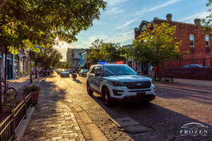 On this summer evening, the sun shines down the brick-paved street as a Dayton Police Cruiser flashes its emergency lights