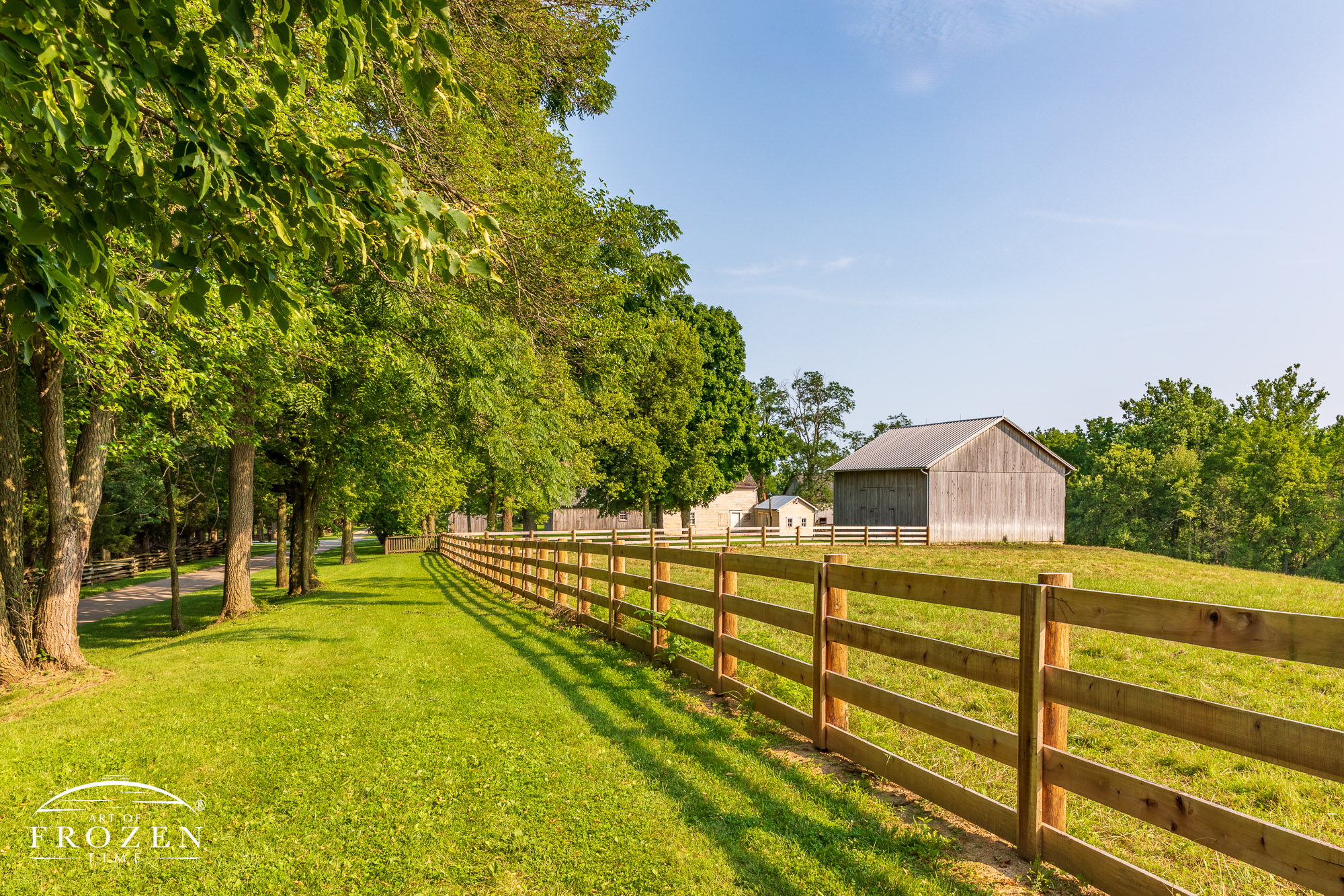 A wooden pasture fence leads the eye towards the historic farmstead at Carriage Hill MetroPark
