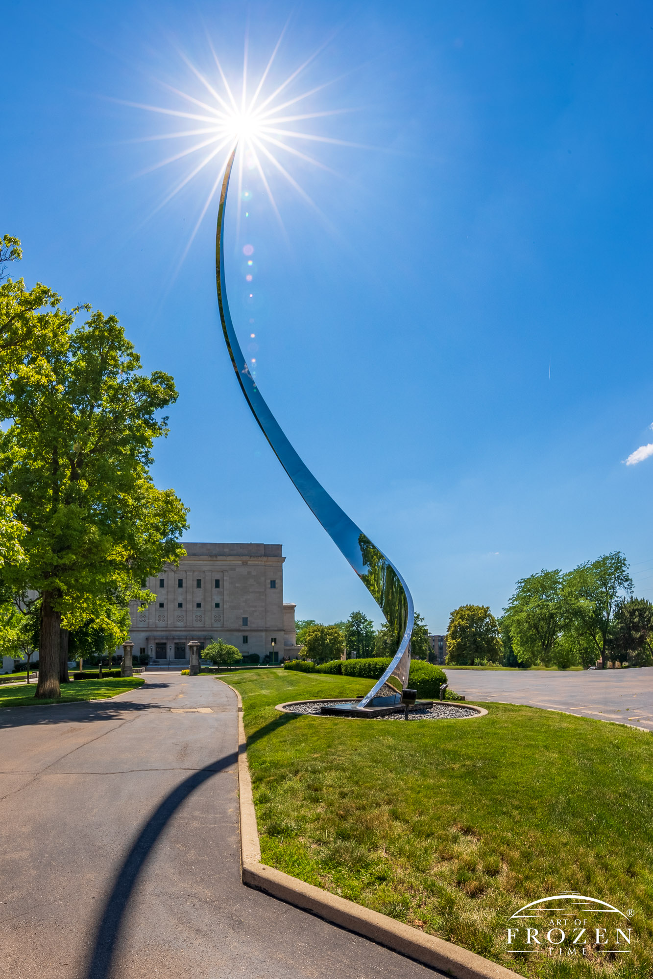 A spiraling stainless steel sculpture at Dayton Art Institute with the sun captured as a starburst on the work’s top tip.