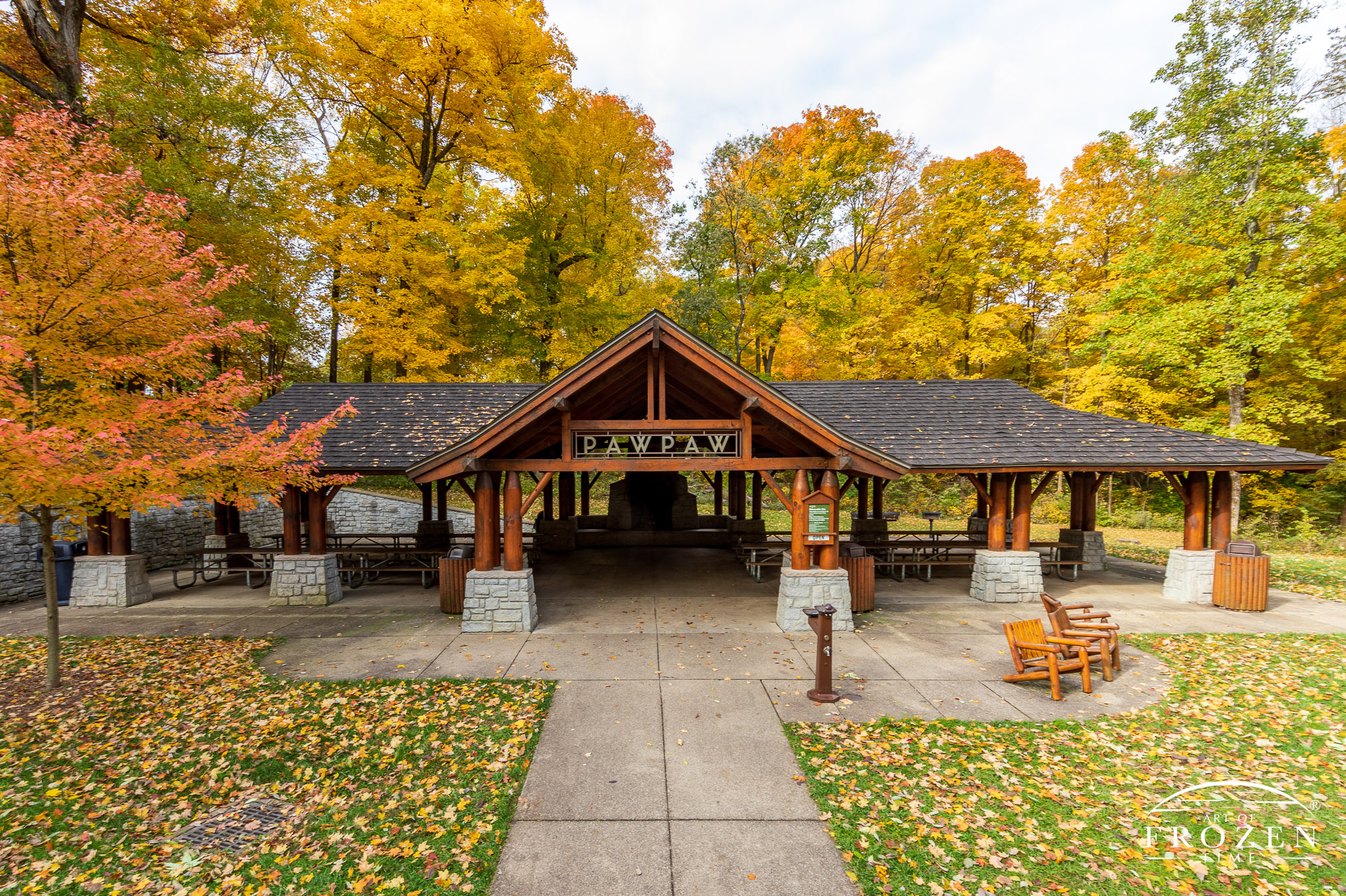 A slightly elevated view of Paw Paw Camp which features an Adirondack picnic shelter surrounded by colorful autumn trees basking in warm light