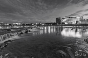 The Great Miami River as it spills over River Run and in the quiet evening forms an eddy wihch occupies the foreground as the Dayton Skyline illuminates the night sky
