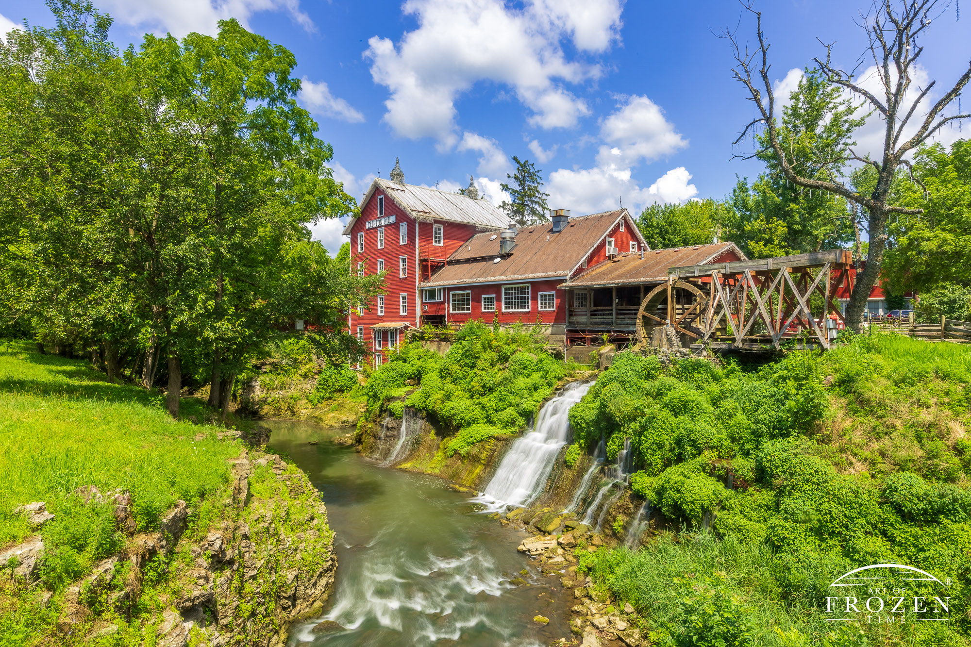 As the Little Miami River powers this grist mill, the red exterior, green plants and blue skies form complementary colors in a classic Ohio scene