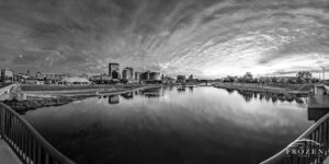 A spectacular sunset over the Dayton Skyline rendered as a black and white panorama where the setting sun illuminates the underside of the clouds making for a dynamic scene