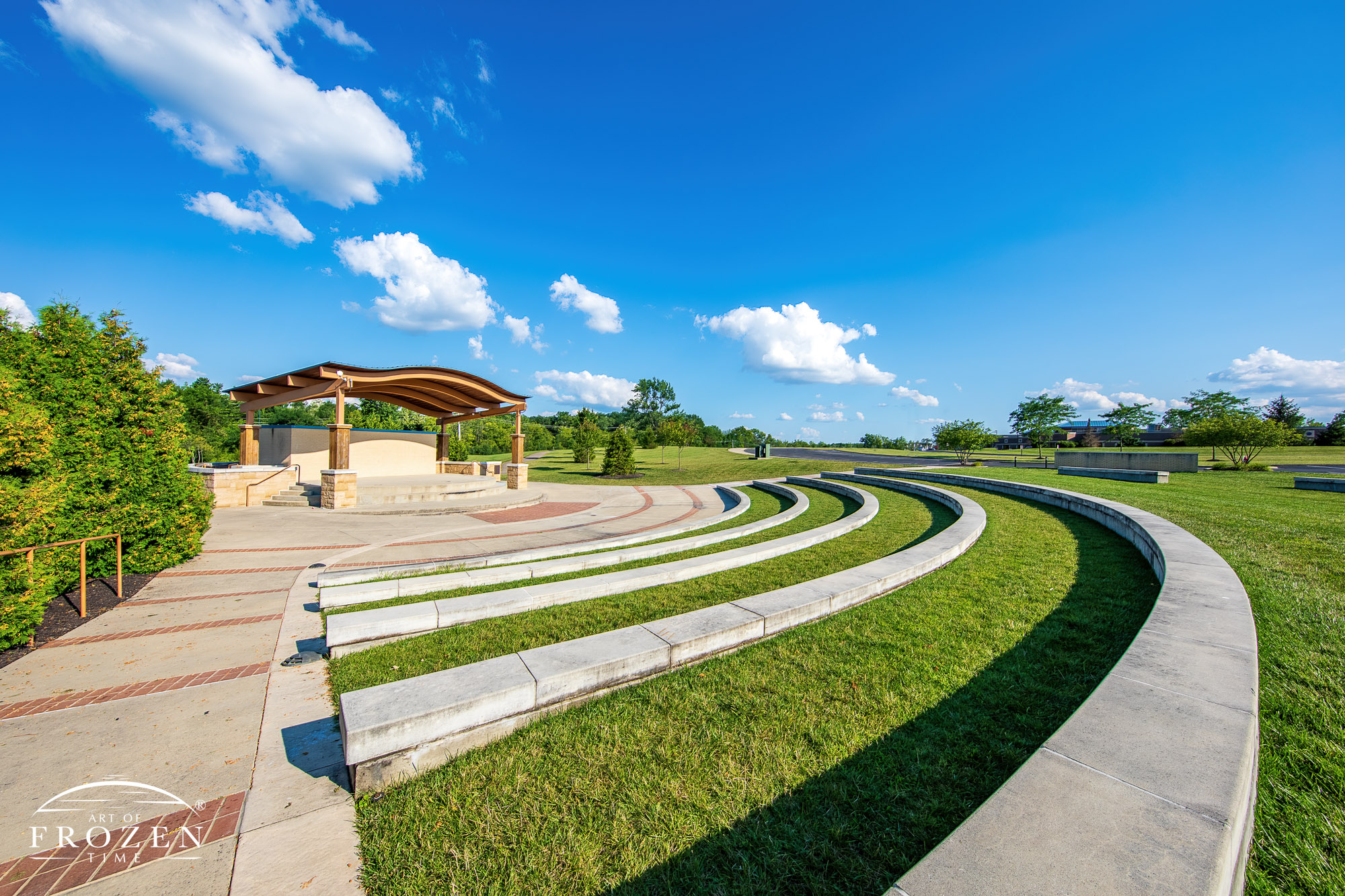 Concentric stone seating platforms arcing around the stage at Eichelberger Amphitheater as cumulous clouds float through the blue sky