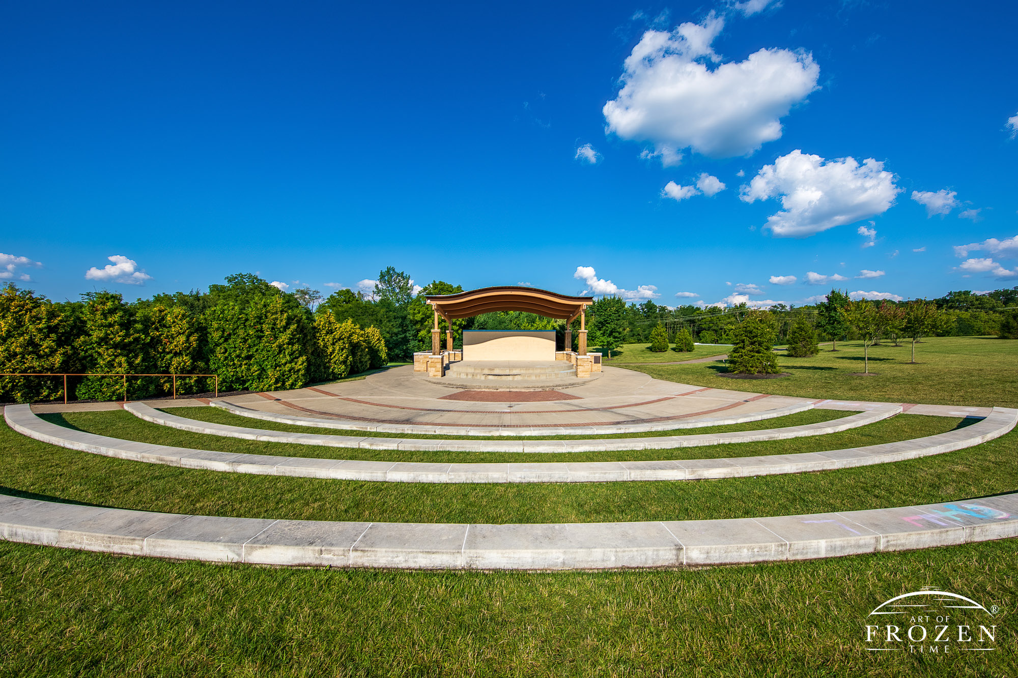 Concentric stone seating platforms arcing around the stage at Eichelberger Amphitheater as cumulous clouds float through the blue sky