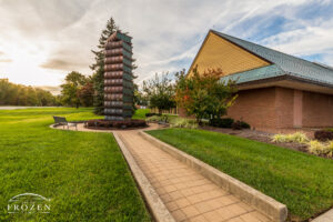 An evening image of a sculpture featuring a stack of ceramic books 22-feet tall symbolic of Centerville Ohio’s 200 years of history