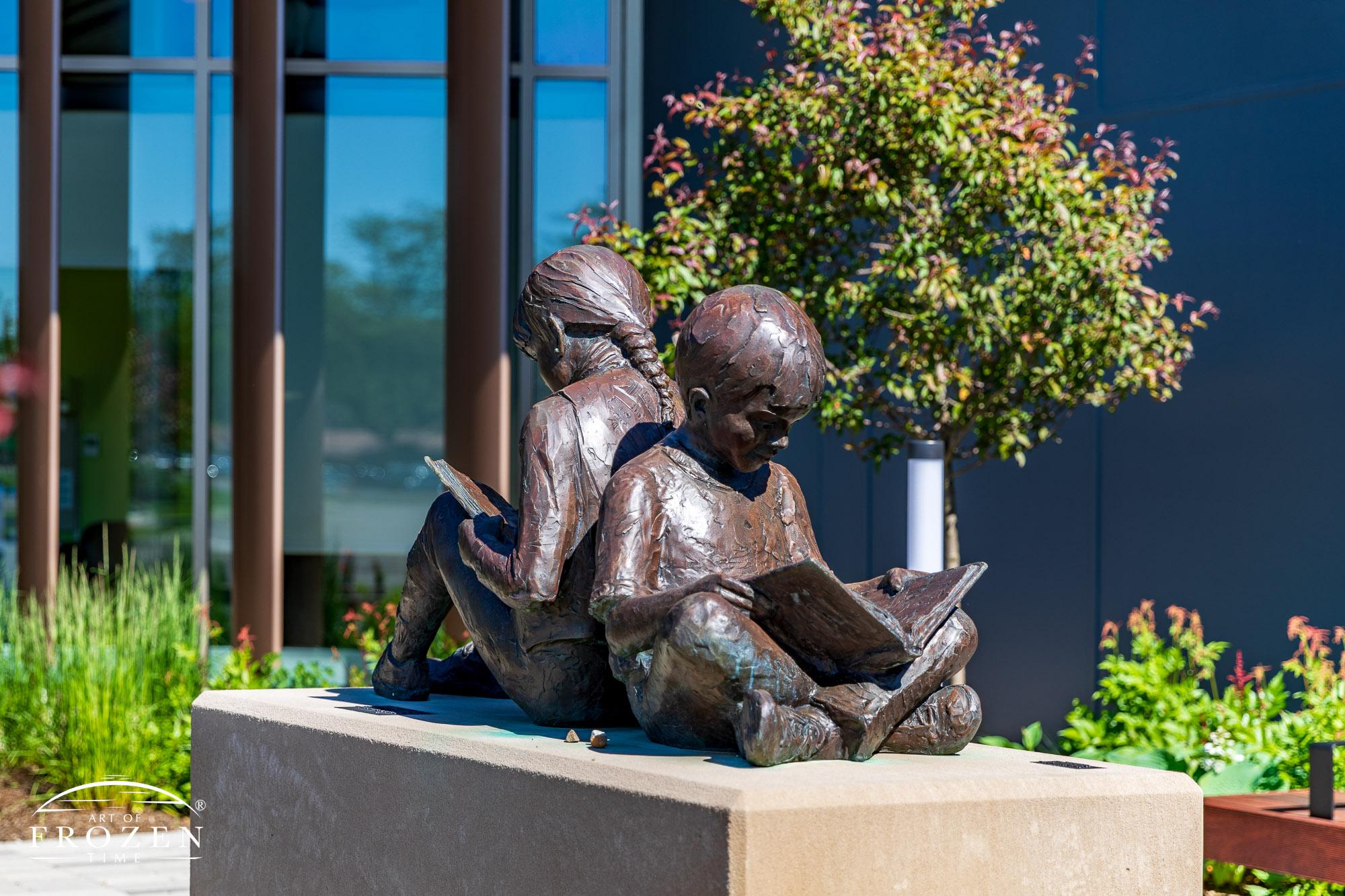 A sculpture of a boy and girl sitting back-to-back engrossed in their respective books