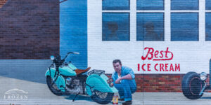 A mural depicting a 1950s diner showing a man tinkering with his classic motorcycle