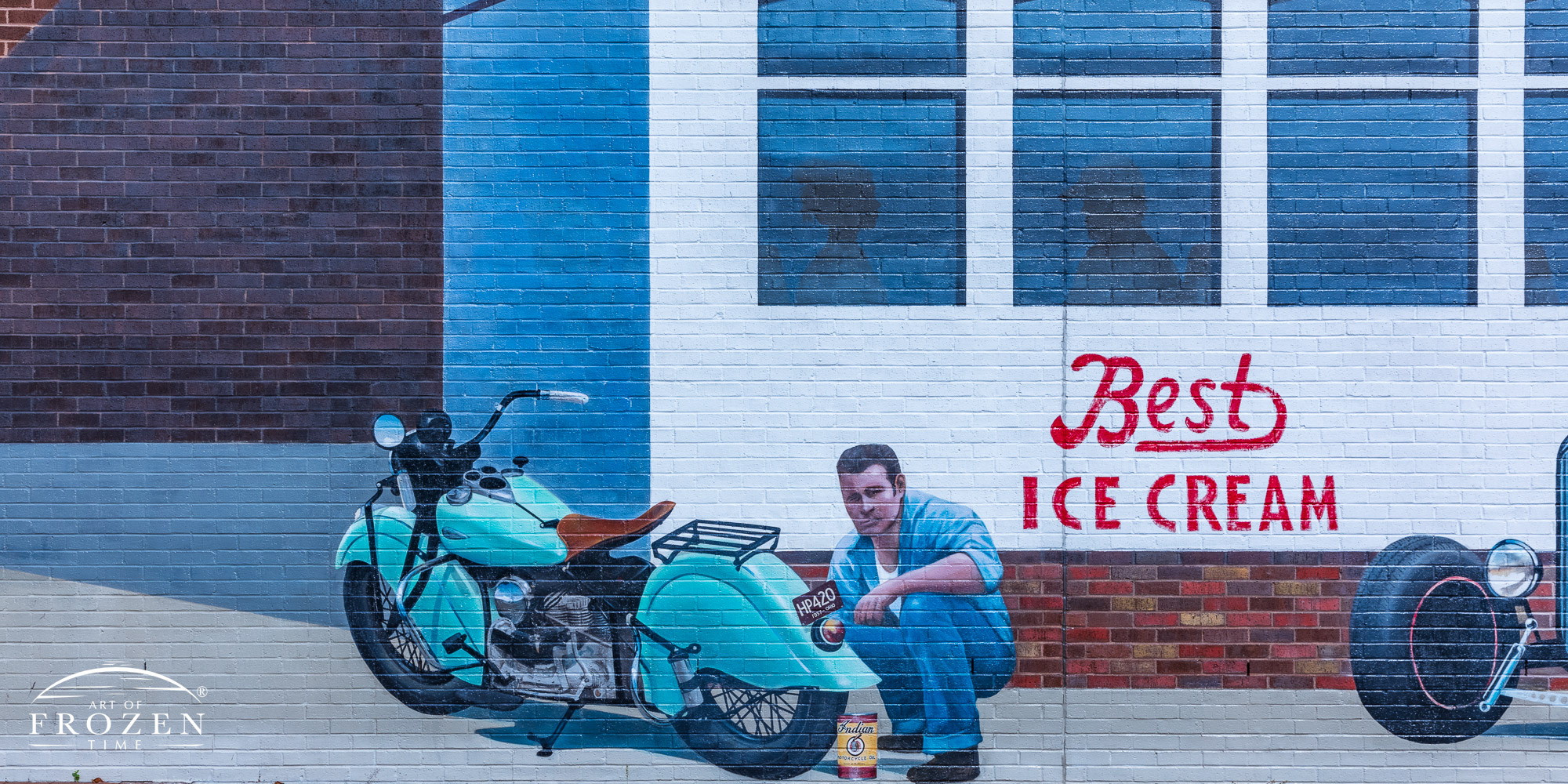 A mural depicting a 1950s diner showing a man tinkering with his classic motorcycle