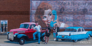 A mural depicting a 1950s diner with period roadsters in front and young adults having conversations