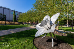 A metal sculpture resembling a large flower resides in downtown Hamilton’s Rotary Park shines in the evening light.