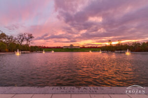 The St Louis Forest Park Grand Basin during a colorful sunset where the sky took on purple hues as the fountain lights illuminate the reflective pool