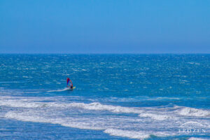 A windsurfer enjoying the blue ocean waters as the overhead sun makes the water sparkle
