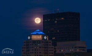 A telephoto image of the full moon rising above the Dayton Skyline which captures the Premier Health and Kettering Towers.