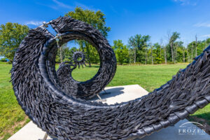 A black sculpture created from cut tires arranged as an uncoiling serpent