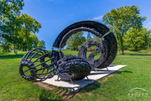 A black sculpture created from cut tires arranged as an uncoiling serpent